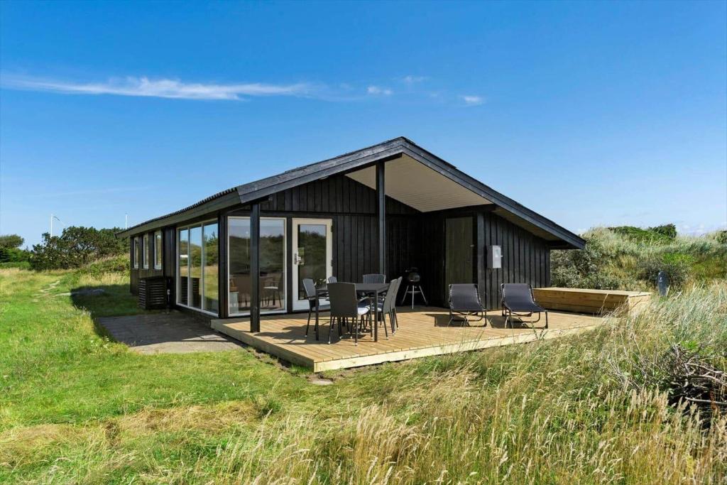 a black house with a deck and chairs in a field at BL1326-Saltum-Svendborgvej-19 in Saltum