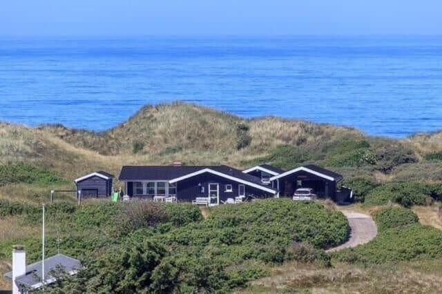 a house sitting on top of a hill next to the ocean at BL1455-Blokhus-Pirupshvarrekrogen-6 in Blokhus
