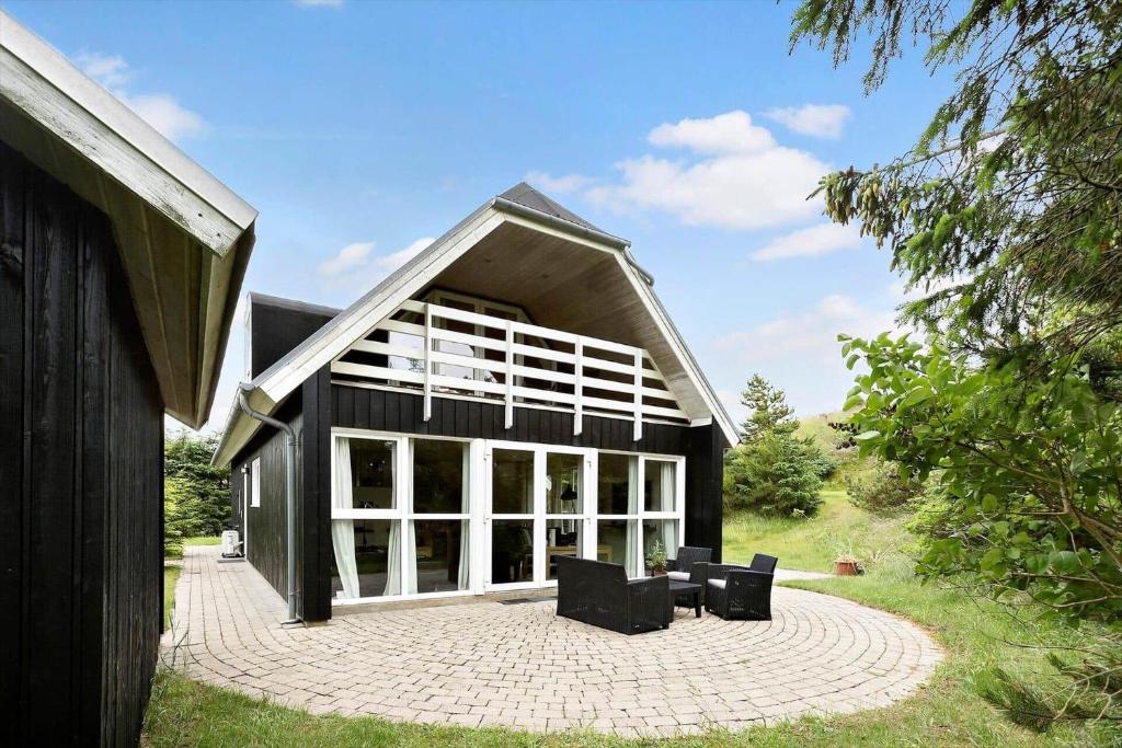 una casa nera con finestre bianche e sedie su un patio di BL381-Blokhus-Maxvej-4 a Blokhus