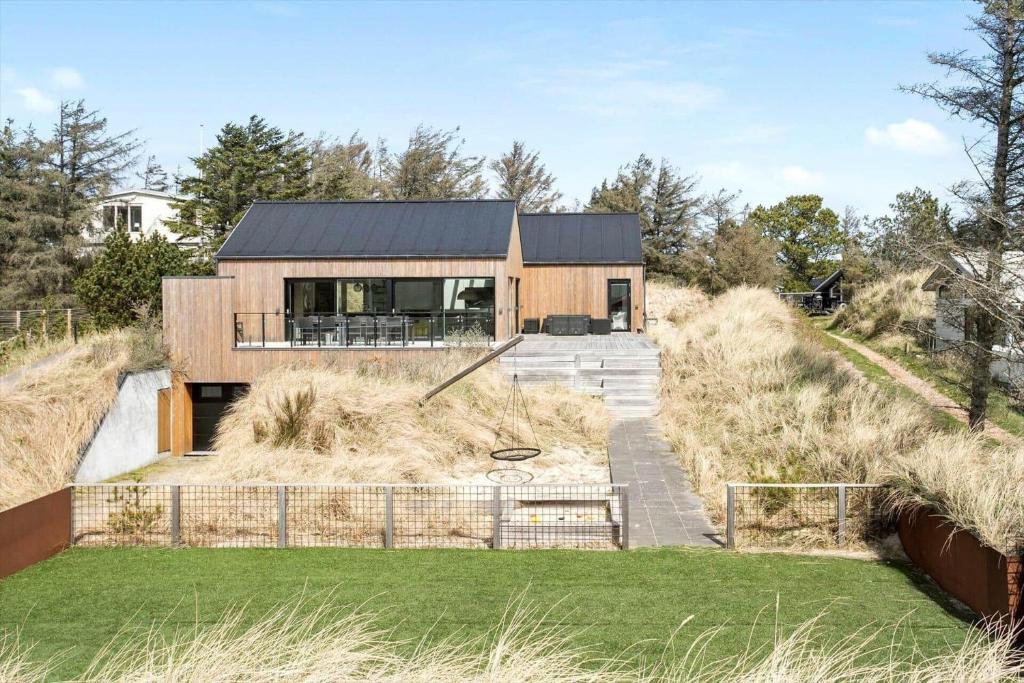 ein Haus mit schwarzem Dach auf einem Hügel in der Unterkunft BL1405 Blokhus - Sletten 12 in Blokhus