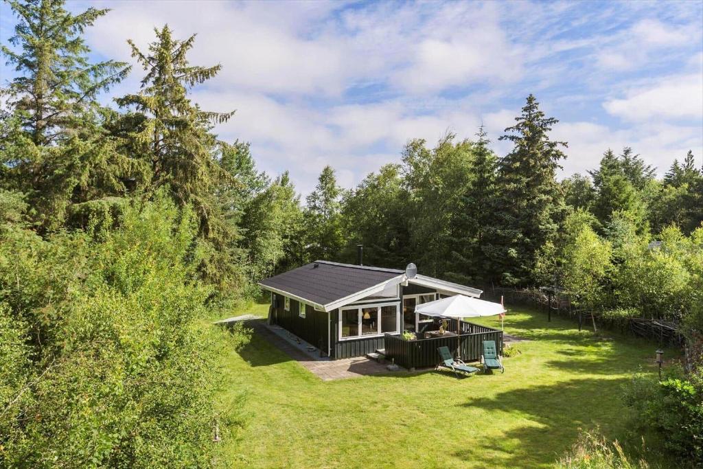 a cabin in the middle of a field with trees at BL1466-Pandrup-Lunekrogen-14 in Pandrup