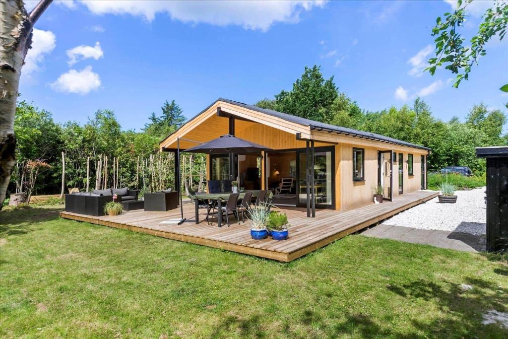 a tiny house with a deck with a table at BL1728-Blokhus-Kaeruldvej-7 in Blokhus