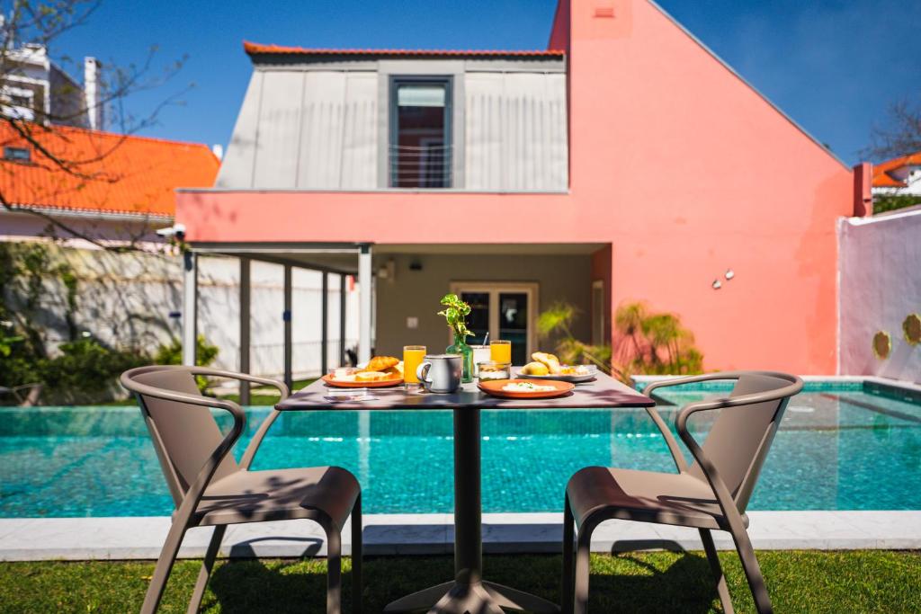 A four-seat outdoor table set beside a turquoise pool in a colourful courtyard.