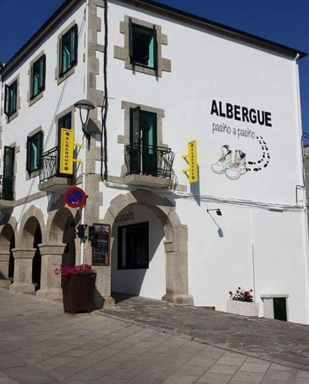 a building with a sign on the side of it at ALBERGUE Pasiño A Pasiño in Portomarin