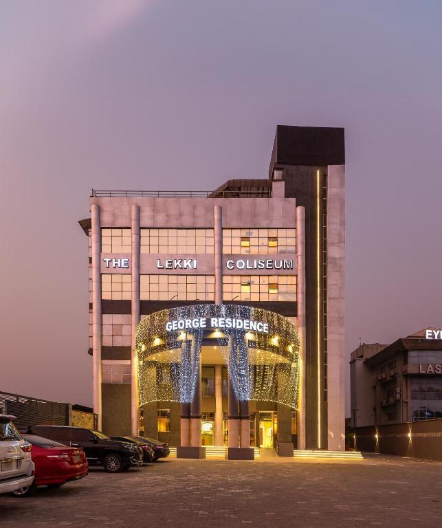 a building with cars parked in a parking lot at George Residence TLC in Lekki