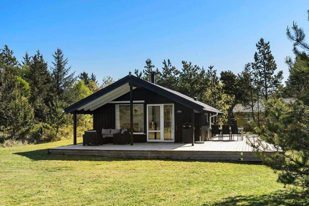 une petite cabine avec une terrasse couverte dans un champ dans l'établissement BL1272-Pandrup-Kirkekrogen-7, à Pandrup