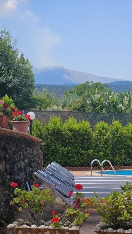 une piscine avec un banc et des fleurs dans un jardin dans l'établissement Villa MELANY Casa Vacanza, à Piedimonte Etneo