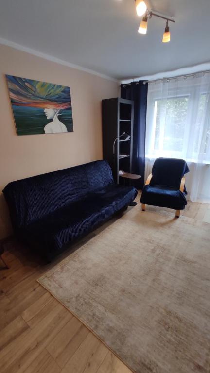 a living room with a bed and a chair at Apartament pod Górą Chełmską in Koszalin