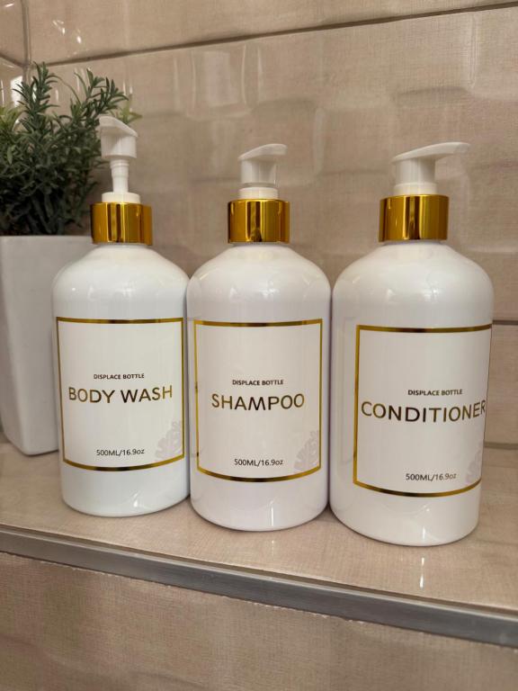 a group of three bottles of soap on a shelf at Local-Lux Apartman 3 szoba, privát parkoló in Kecskemét