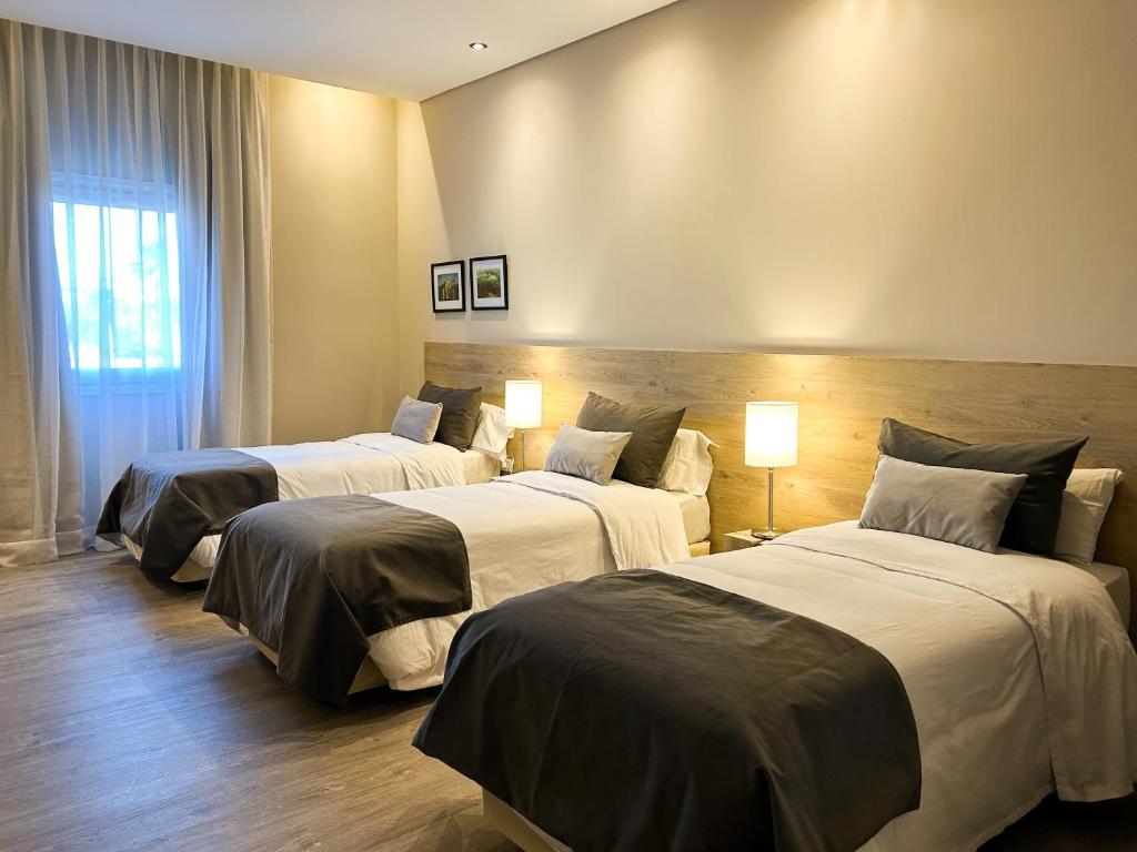 two beds in a hotel room with two lamps at Hotel Finca Alvear in General Alvear
