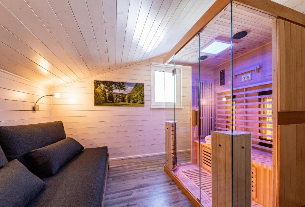 a room with a couch and a glass shower at 2 bis 4 Personen mit Infrarotsauna F2H9 in Ruhla