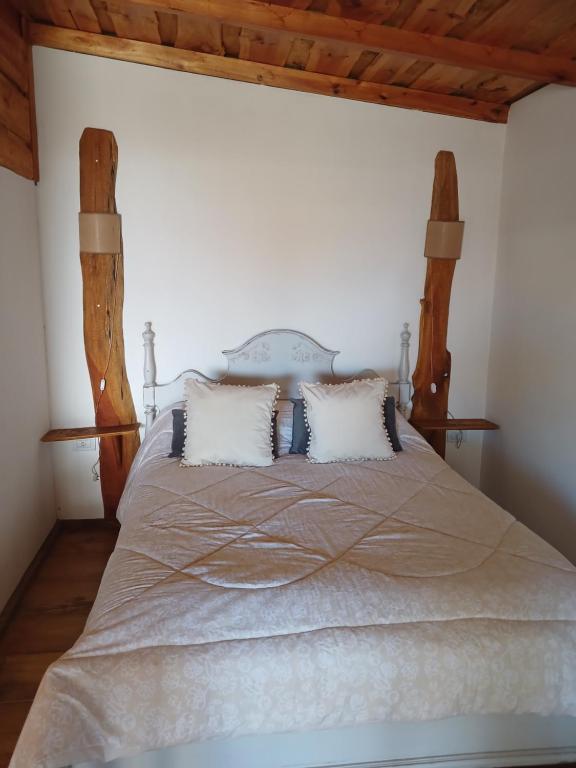 a bedroom with a large bed with two pillows at La Cabaña de Sofi in Tandil