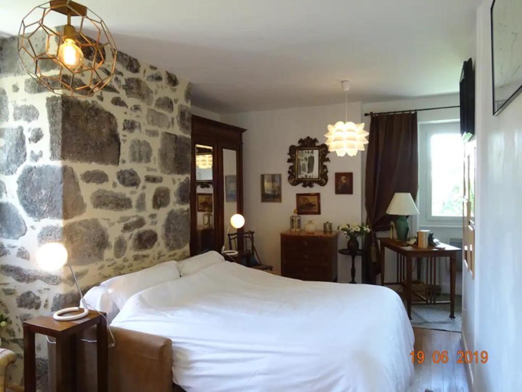 a bedroom with a bed and a stone wall at Villa 3 chambres à Saint-Cirgues-de-Malbert avec piscine in Saint-Cirgues-de-Malbert