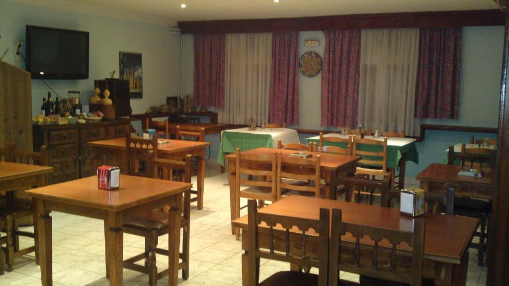 comedor con mesas y sillas y TV en Hotel Peralba, en Aixovall