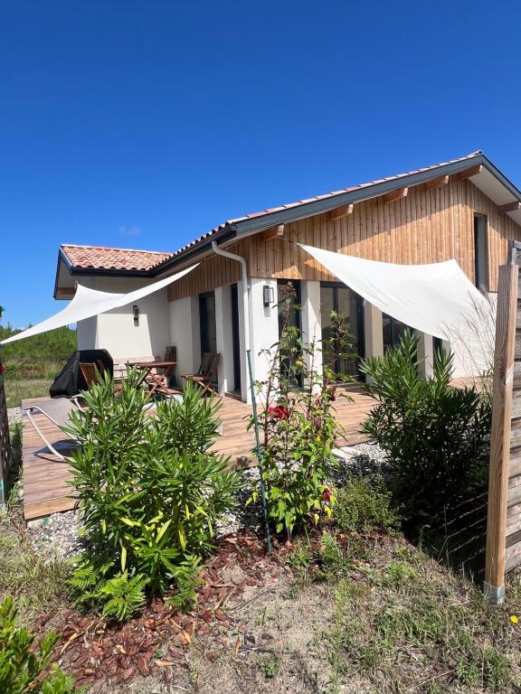 a house with a wooden deck in front of it at Maison entre océan et forêt landaise in Vielle-Saint-Girons