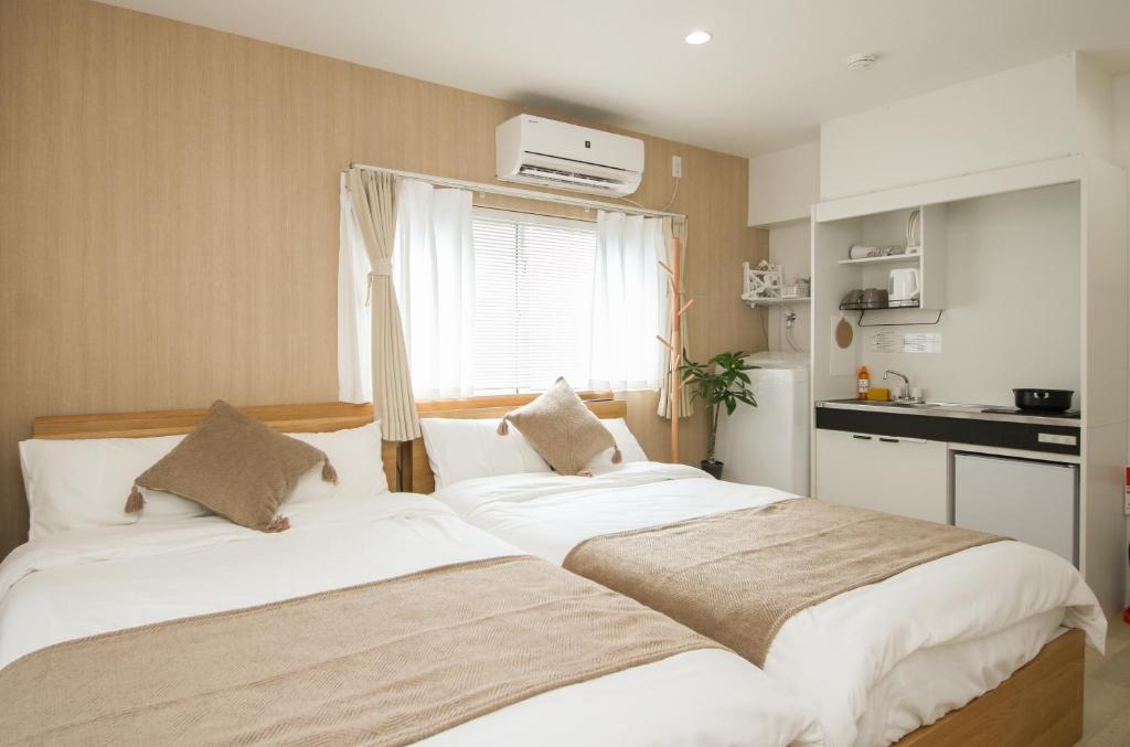 東京にあるTokyo Ueno Mia Hotelのキッチン付きの小さな部屋にベッドが2つあります
