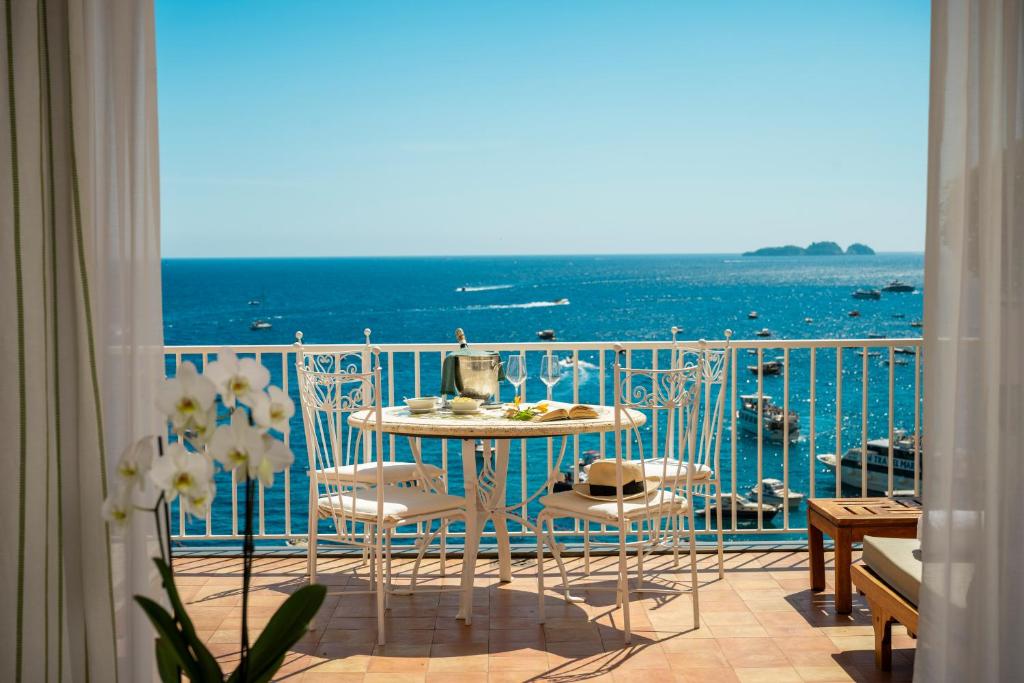 a balcony with a table and chairs and the ocean at Hotel Buca Di Bacco in Positano