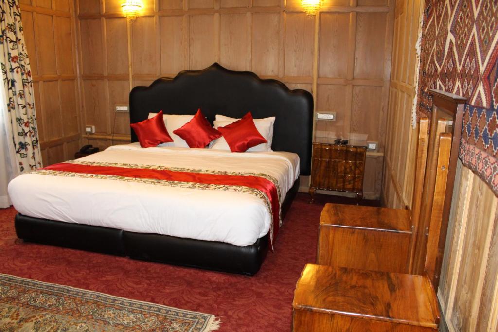 a bedroom with a large bed with red pillows at New York Houseboat in Srinagar