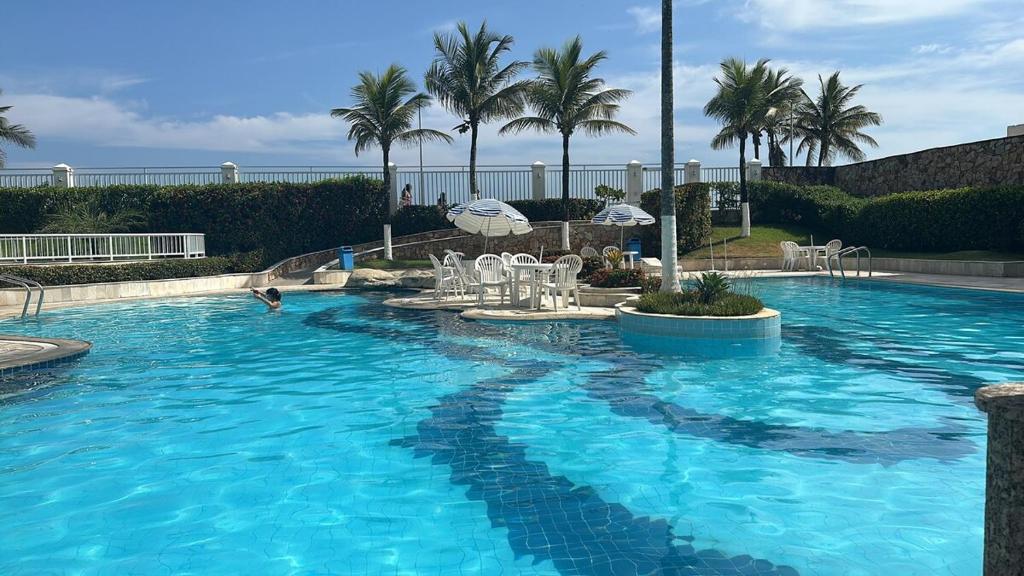 a large blue swimming pool with chairs and palm trees at Maravilhoso flat 2 in Rio de Janeiro