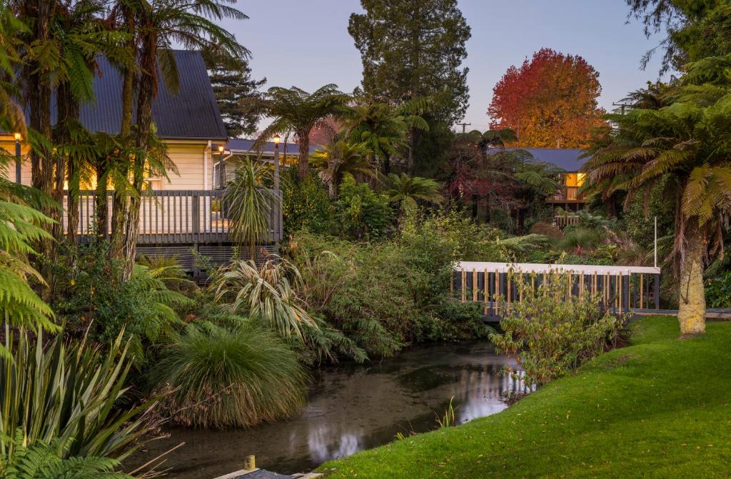 a house with a stream in front of a garden at Best Western Braeside Rotorua in Rotorua