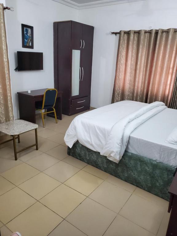 a bedroom with a bed and a desk and a chair at Jagtonsuitesandgarden JPS in Abuja