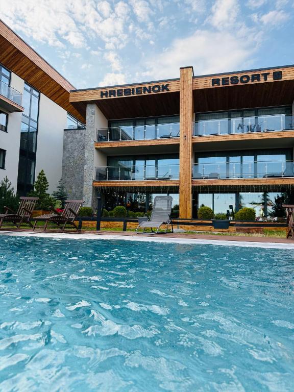 a hotel with a swimming pool in front of a building at Helen Apartments C317 Hrebienok in Starý Smokovec