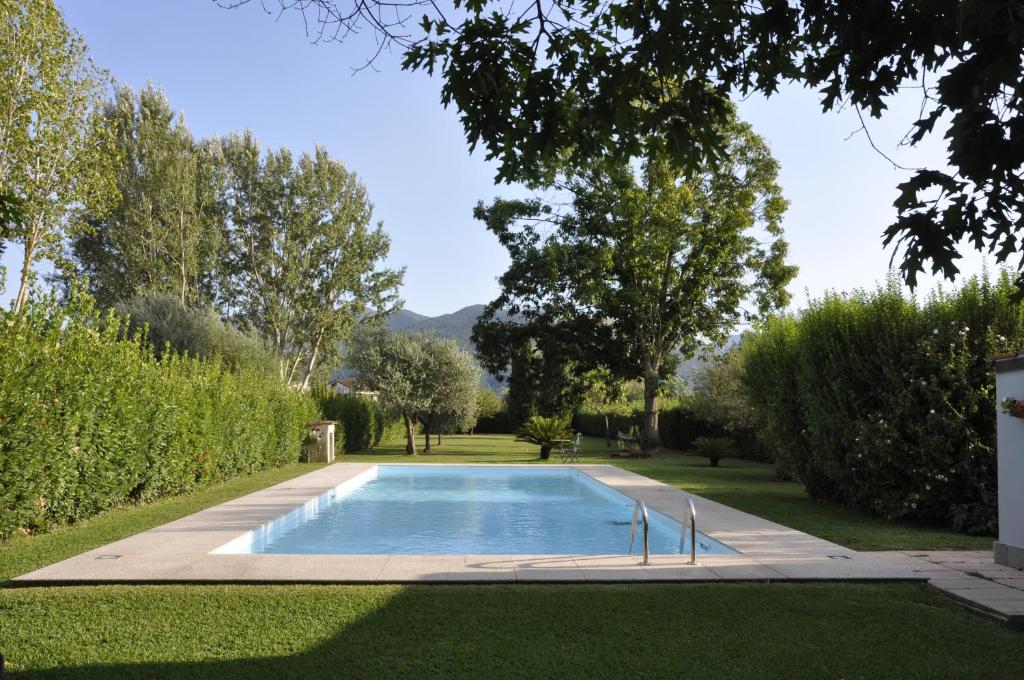 una piscina en un jardín con árboles y césped en La Capannina, en Capannori