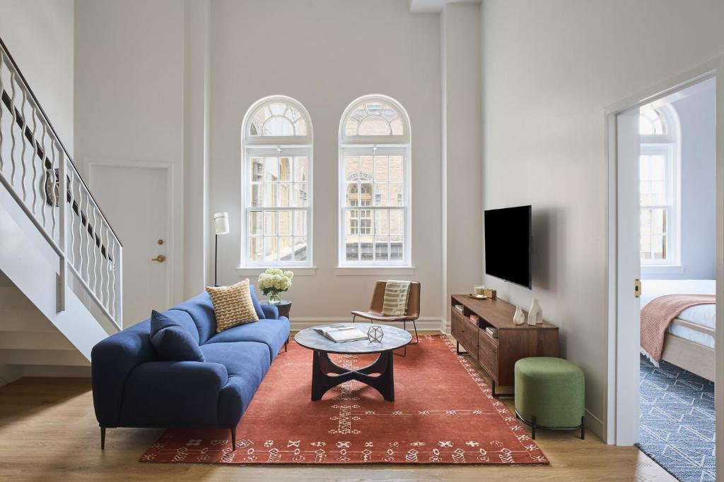 ein Wohnzimmer mit einer blauen Couch und einem Fernseher in der Unterkunft Rusk House Serviced Apartments in Houston