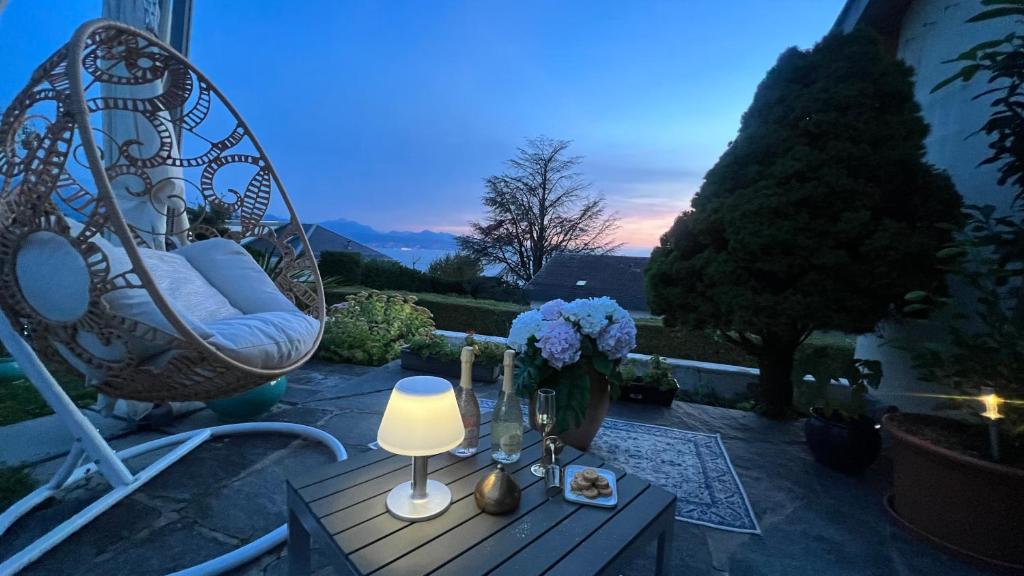 ein Tisch mit einer Lampe und Blumen auf einer Terrasse in der Unterkunft BB Opera in Belmont-sur-Lausanne