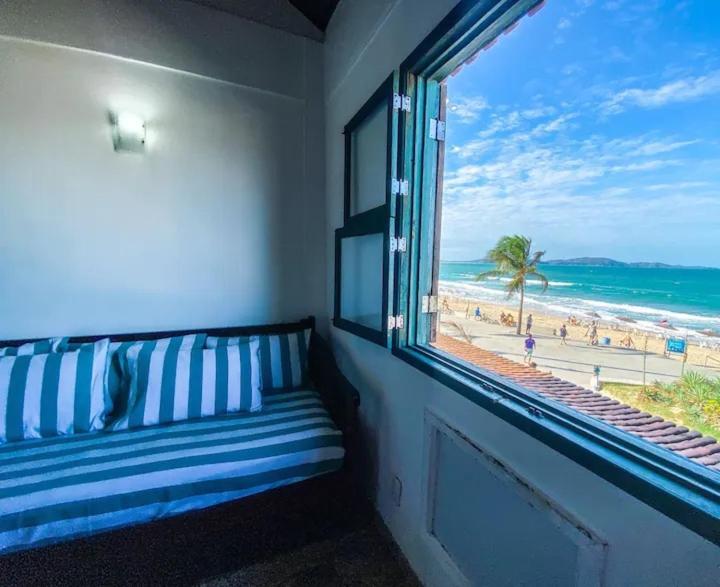a window with a bench looking out at the beach at PERÓ BEIRA MAR - Flat âncora - 203A in Cabo Frio