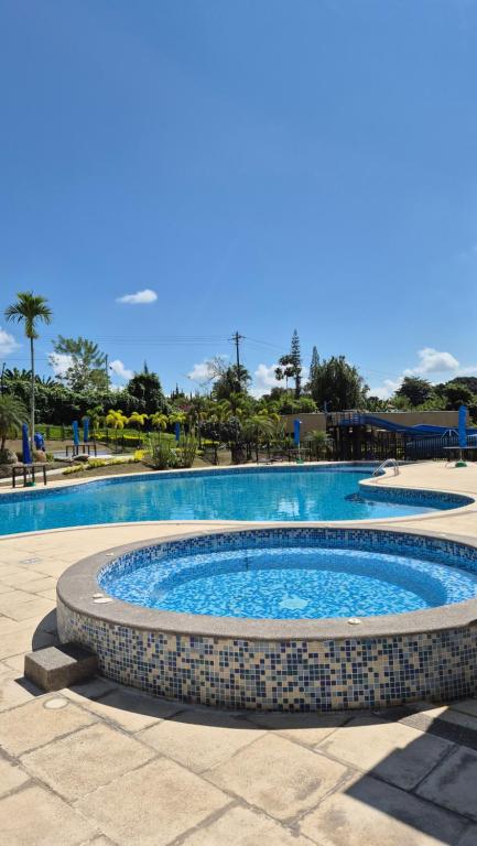 a large swimming pool in a resort with a blue at Apartamento Vacacional a 5min del Aeropuerto - Con 3 Piscinas - 2 Jacuzzi - Sauna - 20 min Parque del Café - By Molca Travel in La Tebaida