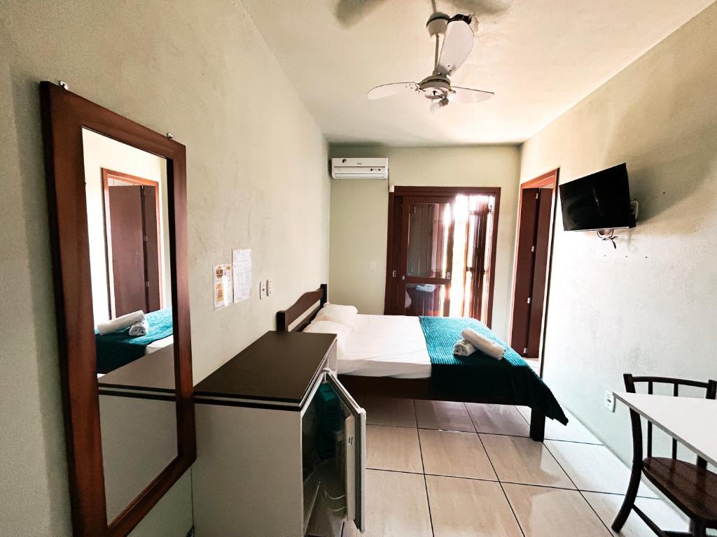 a bedroom with a bed and a tv in a room at Hotel Girassol in Imbé