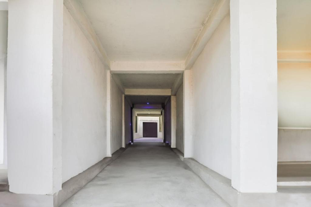 an empty corridor in a building with white walls and columns at SPOT ON Hotel chitransh inn in Lucknow