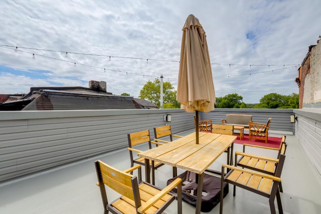 a wooden table and chairs on a balcony with an umbrella at Penthouse Condo with Rooftop Deck in Philadelphia! in Philadelphia