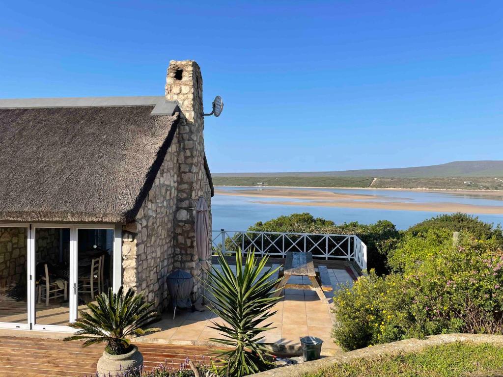 a stone house with a view of a body of water at Under Milkwood in Witsand