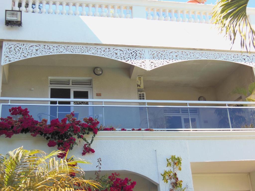 a white house with a balcony with flowers on it at Hôtel Résidence Le Phoenix in Saint-Pierre