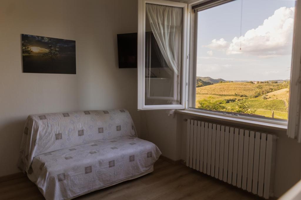 a bedroom with a chair and a large window at I Pesci de Boschi in Borgo Priolo