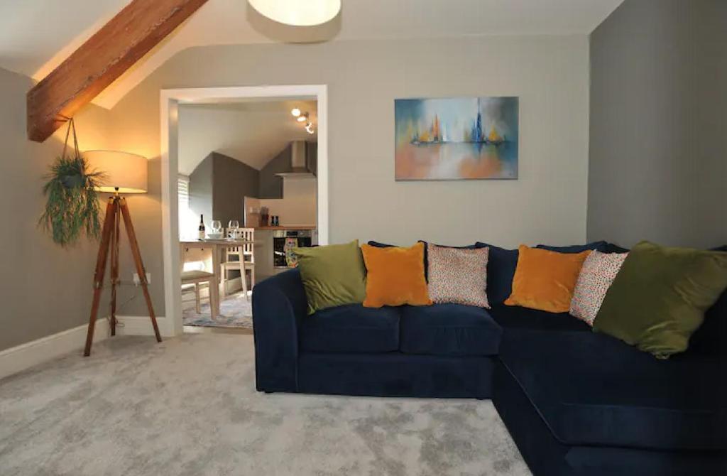 a living room with a blue couch with colorful pillows at Sandpiper Apartment in Benllech