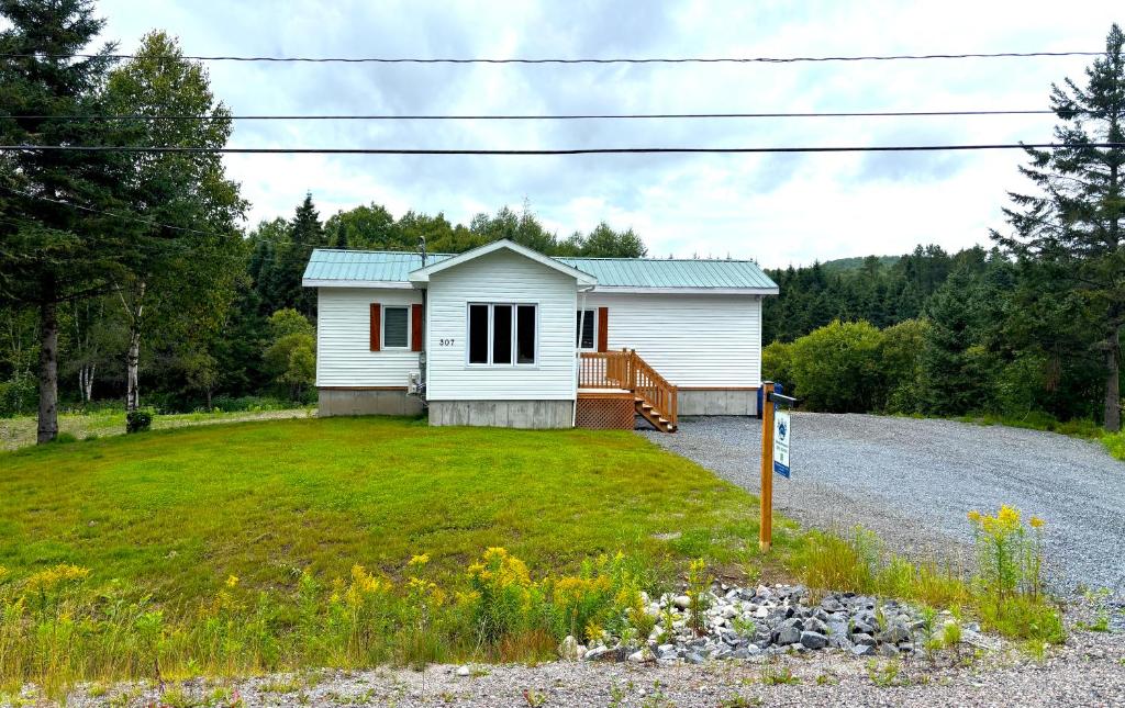 a small white house on a gravel road at Gîte du Ruisseau in Lamarche