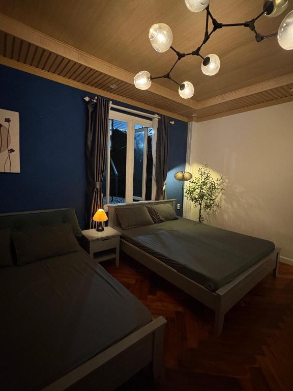 a bedroom with two beds and a blue wall at Hoshi Dalat Fullhouse in Xuan An
