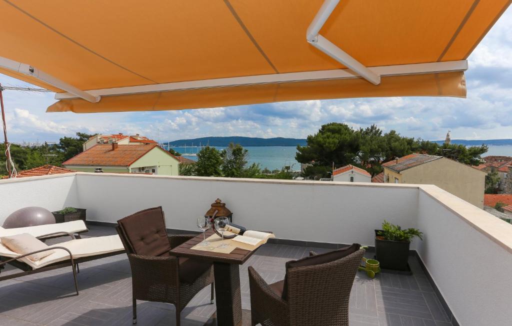 uma varanda com uma mesa e cadeiras e um guarda-sol laranja em Apartments Ena&Toni em Kaštela
