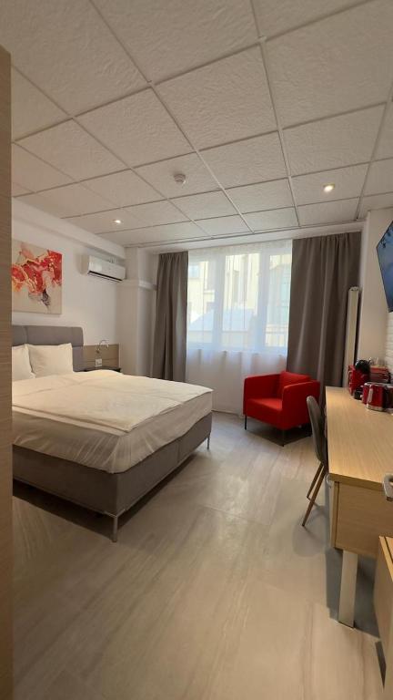 a bedroom with a large bed and a red chair at Heights Accommodation Old Center in Bucharest