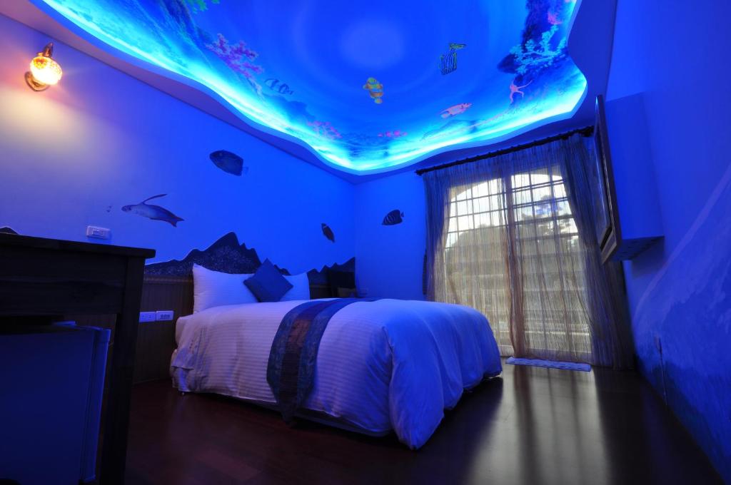 a bedroom with a bed with an aquarium on the ceiling at Siaowan Homestay in Kenting