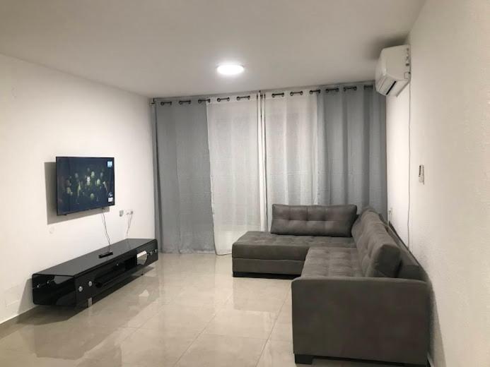 a living room with a couch and a flat screen tv at Isramax 3BR apartment near the sea. in Bat Yam