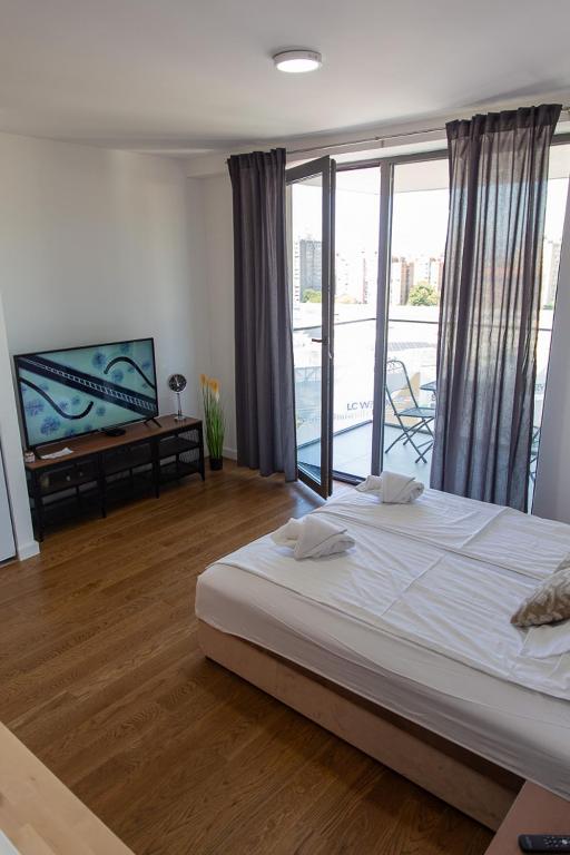 a bedroom with a large bed and a balcony at Planet Residence Royal Studio & SPA in Niš
