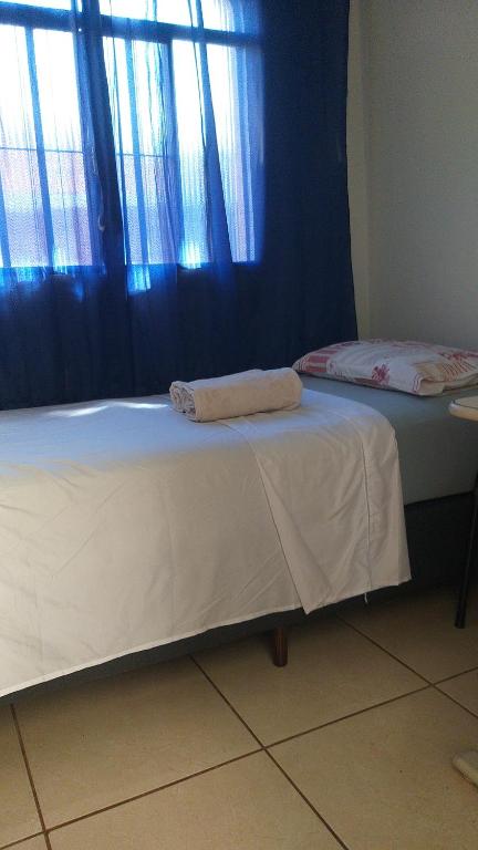 a bed with two towels on it in a room at Quartos em casa compartilhada na Cidade Canção Maringa in Maringá