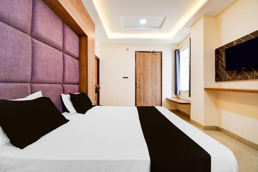 a bedroom with a large white bed with a purple wall at Hotel O Drishti Grand in Lucknow