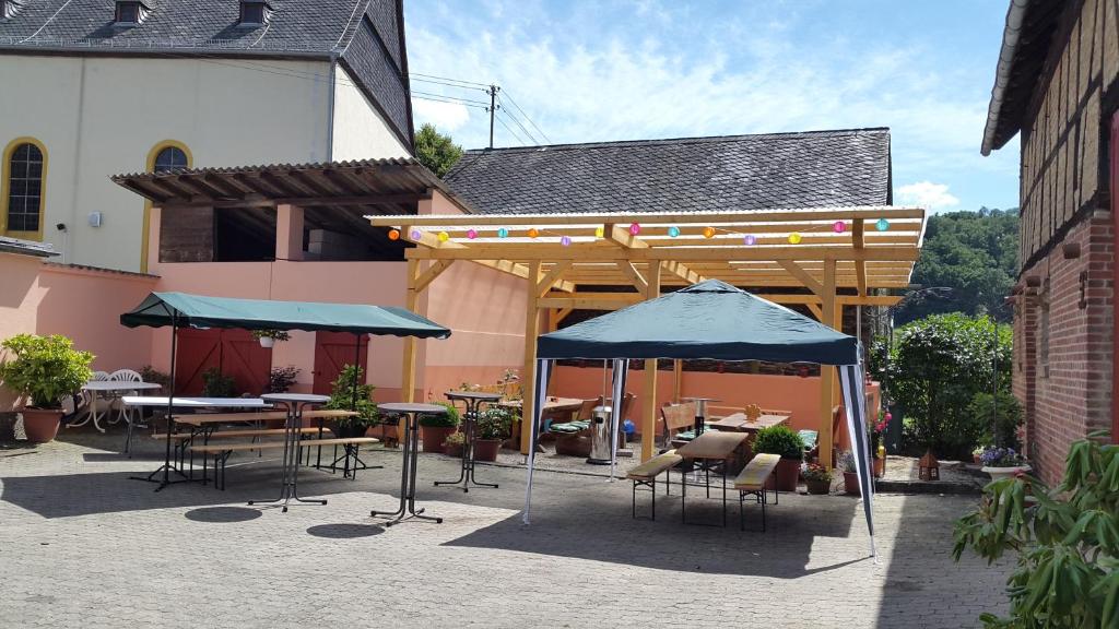 un patio con mesas, sillas y sombrillas en Zur Dorfschänke en Hausen