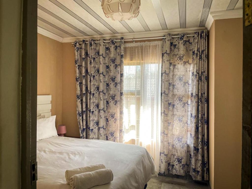 a bedroom with a bed and a window with curtains at 17 Zurich Drive House in Margate