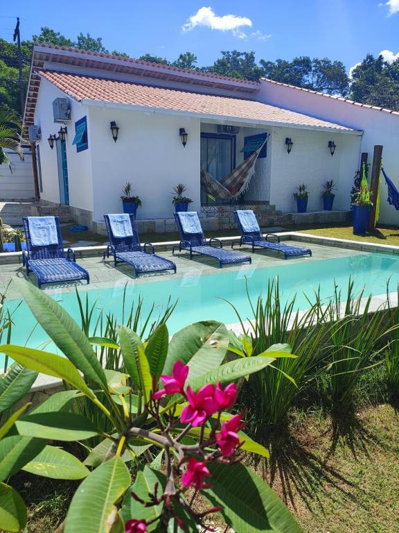 a villa with a swimming pool and chairs at Casa do Aconchego OFICIAL in Pirenópolis